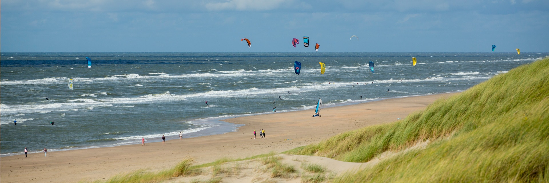 Uitgestrekt strand met allerlei kleurrijke vliegers